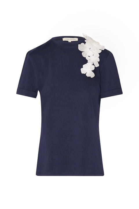 Navy t-shirt with white floral applique at the shoulder.
