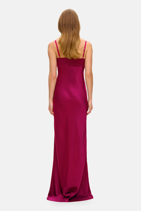 Woman showing the back of a long magenta dress on a white background