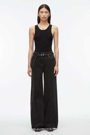 Woman wears compact knit tank top in black with black belted pants.