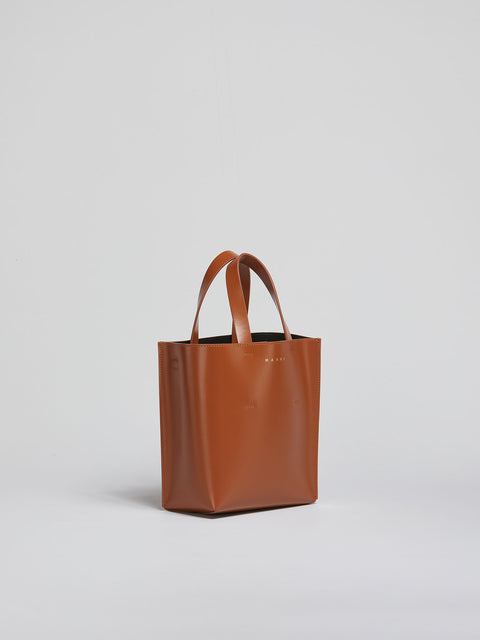 Brown leather tote bag on a light gray background