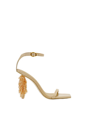 Beige high-heeled sandal with orange tassel on a white background