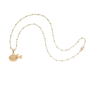 Gold beaded satellite necklace with a gold puffer fish pendant on a white background