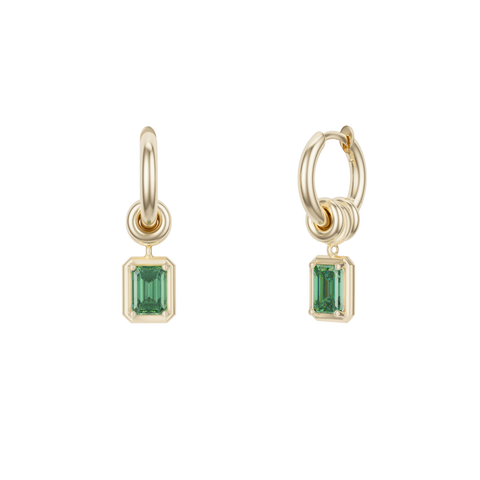 Ghost image of small, yellow gold hoop earring that features three yellow gold annulets, one with an emerald cut emerald stone charm.