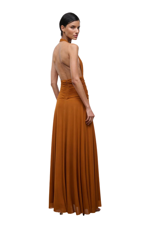 Woman wearing a rust-colored halter neck gown on a white background