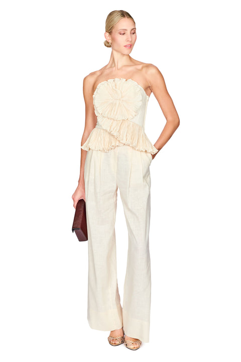 Woman wearing a strapless beige flower top with wide leg beige pants on a white background