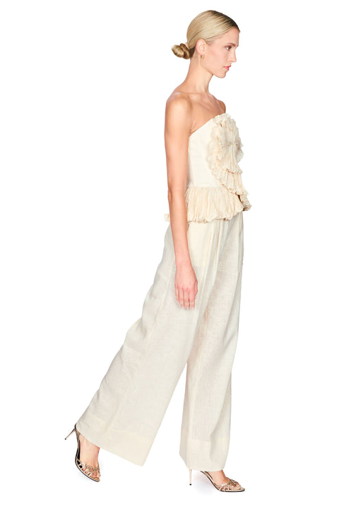Woman wearing a strapless beige flower top with wide leg beige pants on a white background