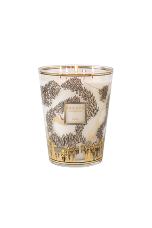 A five-wick scented candle in a clear glass jar with a white wax base, decorated with a gold and brown forest and ski illustration.