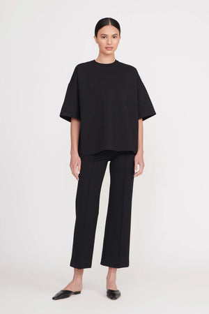 Woman wearing cropped black pants that feature a center seam down the front, paired with a matching oversized black t-shirt.