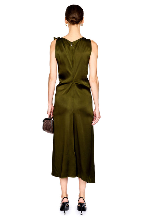 A woman viewed from the back wearing a sleeveless olive green satin midi dress with a tied waist detail, paired with black heels and holding a small brown handbag, against a plain white background.