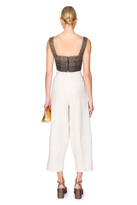 Woman from the back wearing a black and tan woven bustier crop top and white pants on a white background
