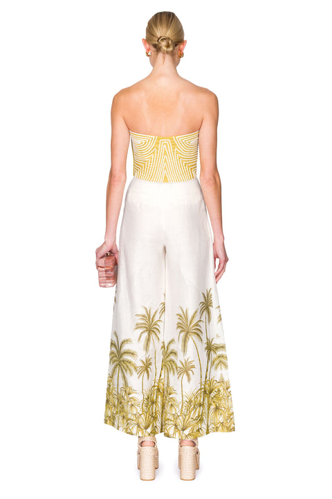 Back view of strapless green bustier top with white piping and white linen palazzo pants with palm tree patterning