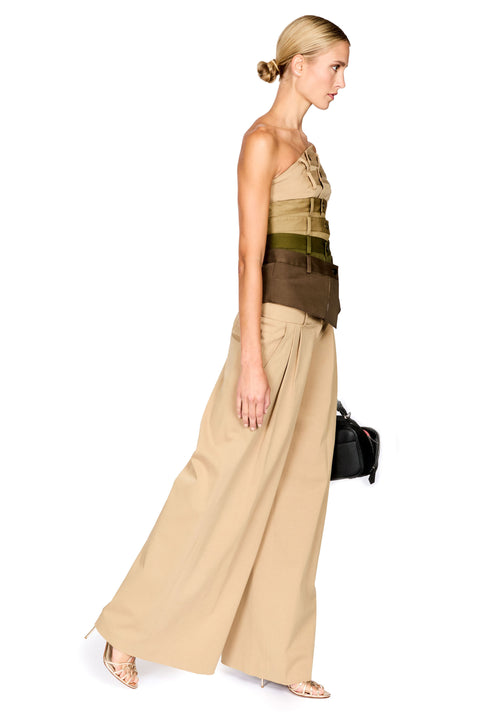 A woman modeling a beige strapless top with a structured waist and matching wide-leg beige trousers, shown in profile against a plain white background.