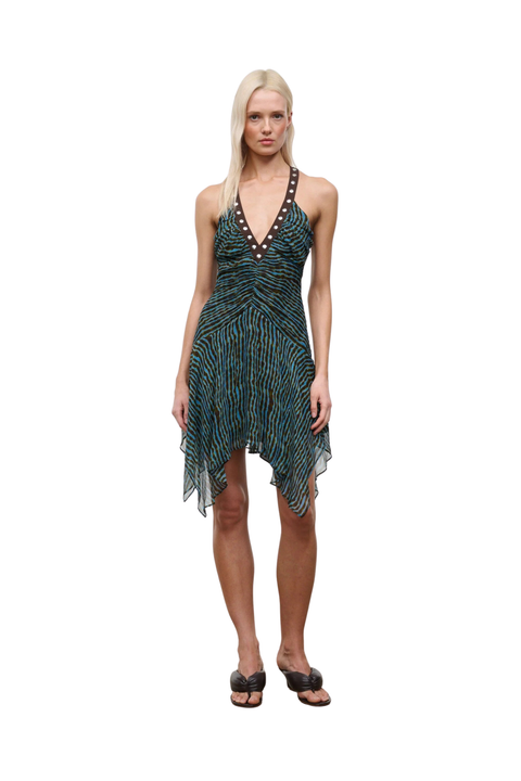 Woman wearing a patterned blue and brown dress with studs on a white background