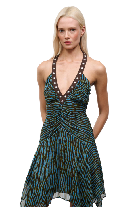 Woman wearing a patterned blue and brown dress with studs on a white background close-up