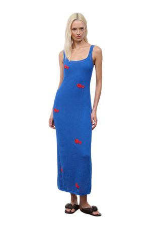 Woman wearing a blue crochet dress with red fish embroidery patterns on a white background