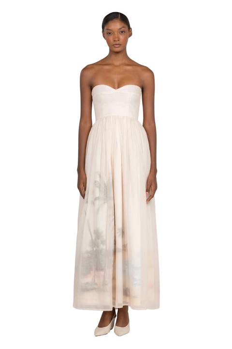 A woman wearing a cream strapless maxi gown with a sweetheart neckline on a white background
