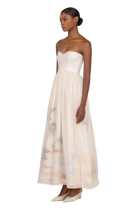 A woman wearing a cream strapless maxi gown with a sweetheart neckline on a white background