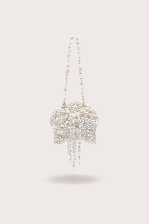 A white, pearl-beaded wristlet crafted to resemble a blooming flower. 