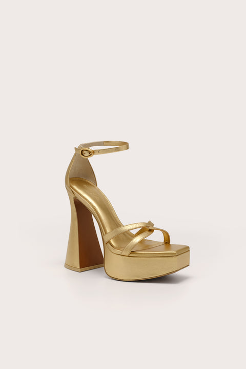 A metallic gold platform sandal with crisscross toe straps, and ankle strap, and a 5.5" heel. 