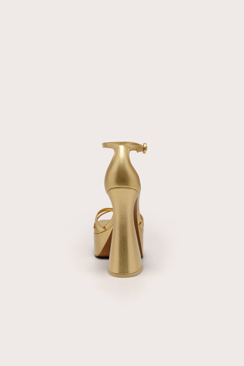 Back-facing metallic gold platform sandal with crisscross toe straps, and ankle strap, and a 5.5" heel. 