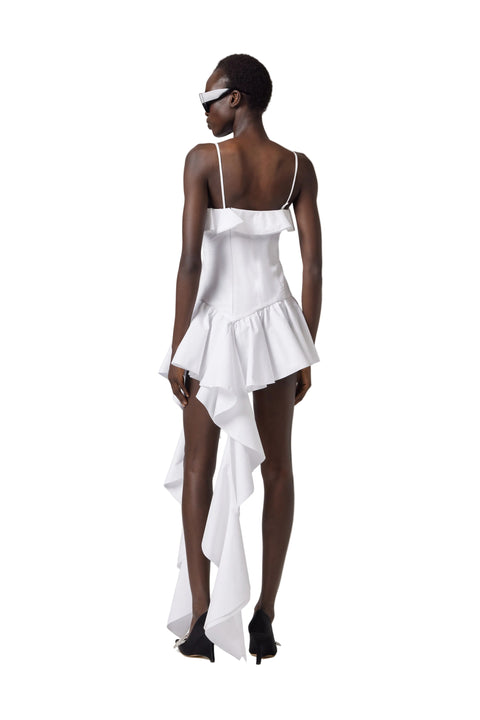 Woman wearing a white dress with ruffled layers on a plain background