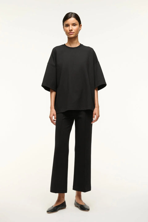Woman wearing a black oversized knit t-shirt with matching cropped pants. 
