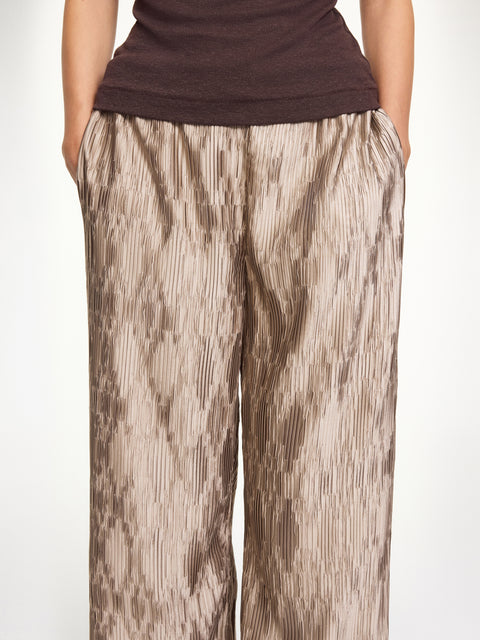 Close up of a woman wearing light brown textured pants with a dark brown tank top. 