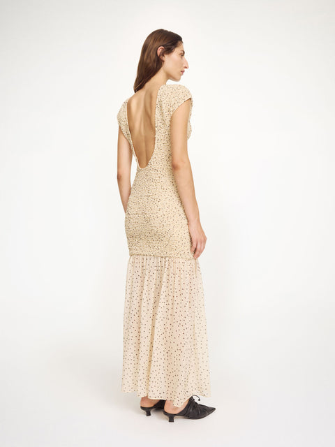 Woman wearing a beige midi dress with black polka dots and a low back design on a white background