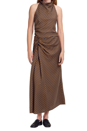 A model wearing a brown and black checkered halter-neck top and maxi skirt with a gathered side detail, paired with black loafers, against a plain white background.