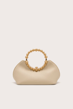 A cream leather handbag that features a gold beaded top handle.  