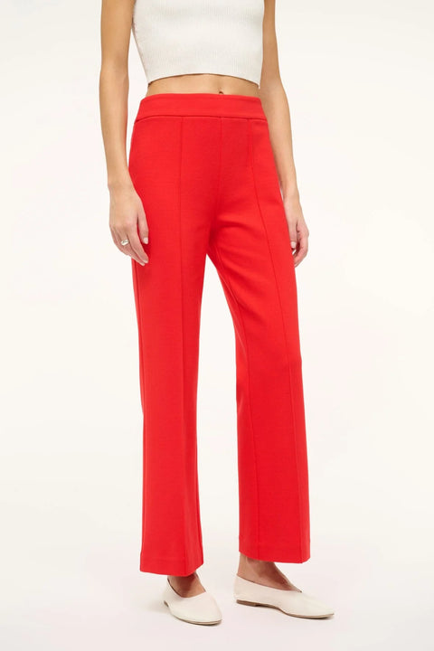 Close up of a woman wearing bright red crop flare pants with a front center seam, paired with a white tank and white flats. 
