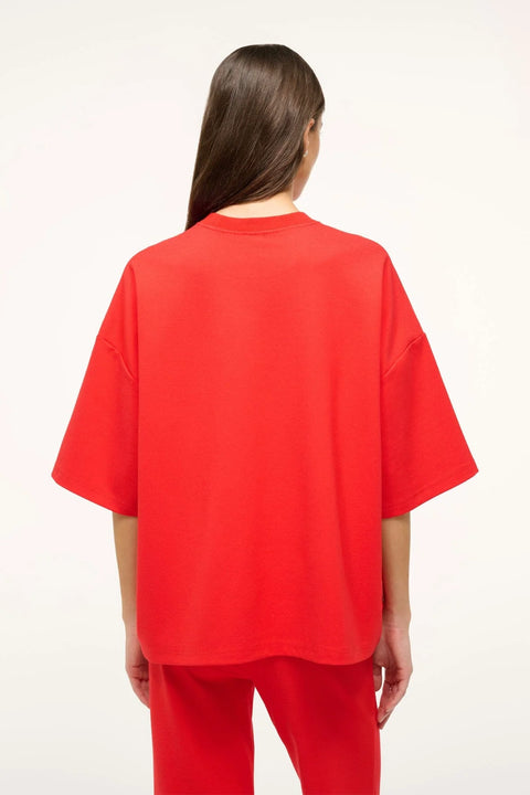 Back-facing woman wearing a bright red oversized, boxy-fit t-shirt with matching pants. 