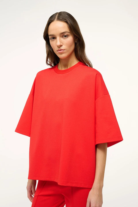 Side-facing woman wearing a bright red oversized, boxy-fit t-shirt with matching pants. 