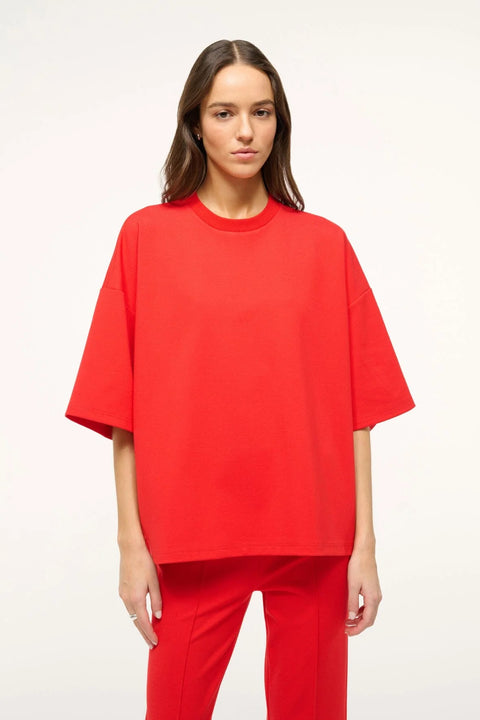 Woman wearing a bright red oversized, boxy-fit t-shirt with matching pants. 