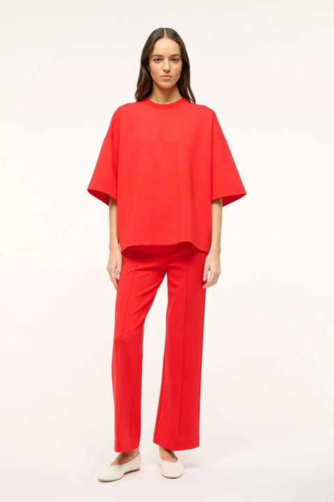 Woman wearing a bright red oversized, boxy-fit t-shirt with matching pants and white flats. 