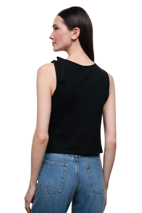 A woman shown from the back wearing a black sleeveless knit top with a side tie detail and blue jeans, photographed against a plain white background.
