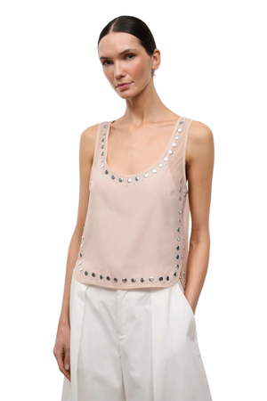 A woman wearing a pink sheer organza sleeveless top with studs front