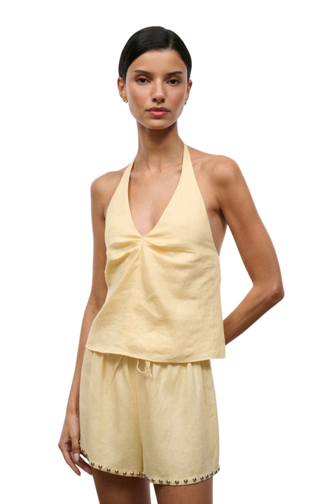 Woman wearing a yellow halter top and shorts set on a white background