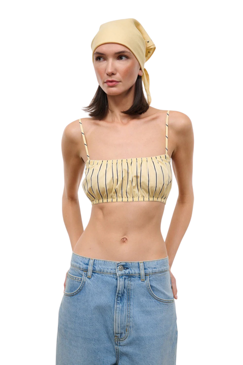 Woman wearing a yellow striped crop top on a white background close up