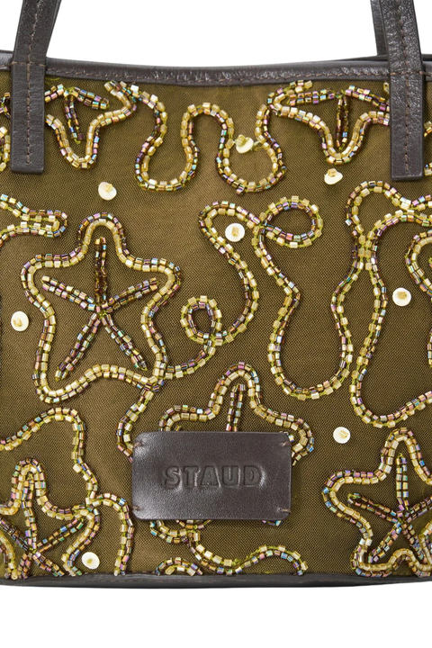 Gold and green star-patterned handbag with black handle on a white background close up beading