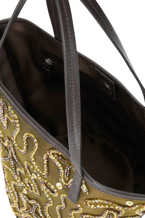 Gold and green star-patterned handbag with black handle on a white background close up inside angle