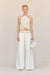 Woman wearing white, white leg jeans that feature a gold chain belt detail, paired with a white crochet top. 