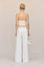 Back view of a woman wearing white, white leg jeans that feature a gold chain belt detail, paired with a white crochet top. 