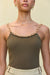 Close up of a woman wearing an olive green knit tank top that features a gold-toned chain detail for straps and across the neckline, paired with cream shorts. 