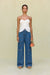 Woman wearing blue denim high-rise, wide leg jeans that feature cargo pockets and contrast stitching, paired with a white strapless top. 