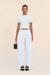Woman wearing a pair of white, barrel-leg cargo pants, paired with a white top, black sandals, and black handbag,