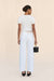 Back-facing woman wearing a pair of white, barrel-leg cargo pants, paired with a white top, black sandals, and black handbag.