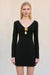 Woman wearing a black long sleeve, mini dress that features a keyhole cutout at the bust and a gold floral hardware detail. 