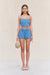 Woman wearing blue denim cargo shorts with a matching blue denim corset, paired with a woven handbag. 