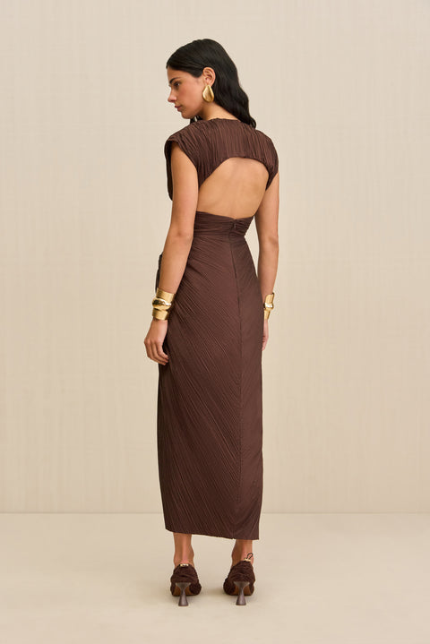 Back-facing woman wearing a structured brown midi dress crafted from a plisse fabric that features a mock neck and open back design, paired with brown heels. 
